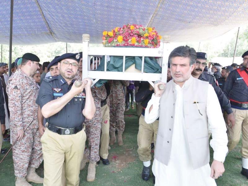 sindh igp dr syed kaleem imam carries the body of one of the two police personnel martyred in a targeted attack on monday morning photo online