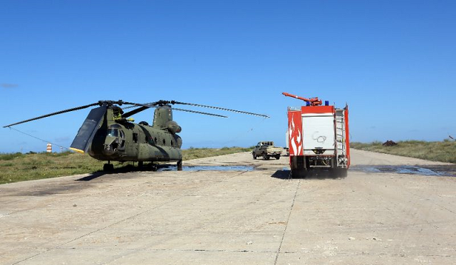 in this file photo a firefighting truck is parked next to an italian built libyan chinook ch 47 military helicopter that was hit by shrapnel following an air strike at mitiga international airport in early april photo afp