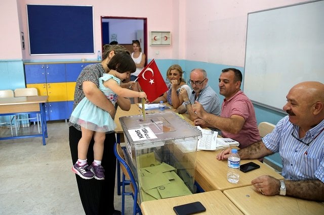 a woman holds a child who casts a ballot at a polling station during a mayoral election re run in istanbul turkey june 23 2019 photo reuters