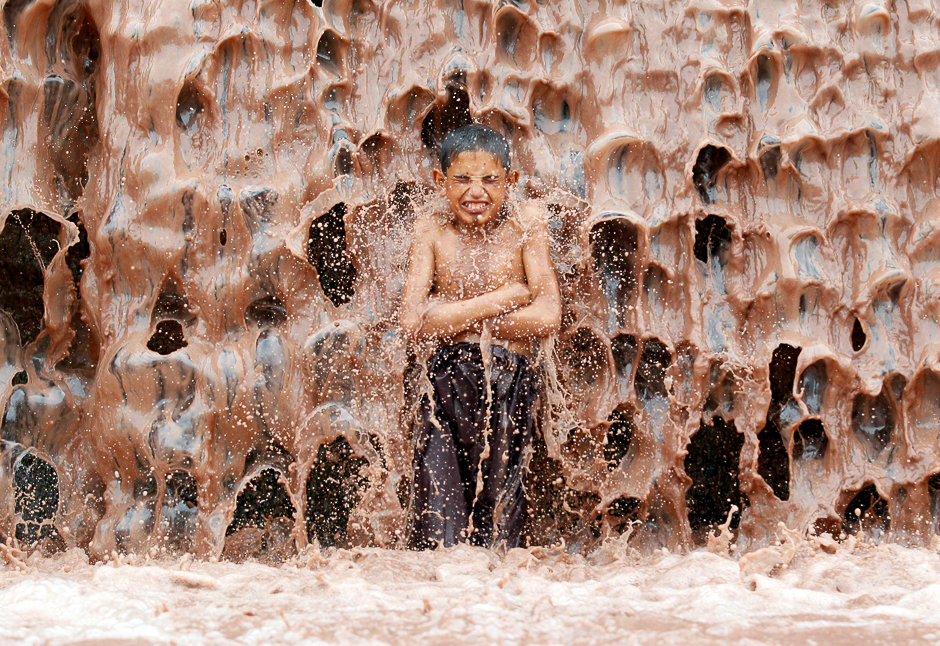 an afghan boy cools off under a muddy waterfall on the outskirts of jalalabad province afghanistan photo reuters