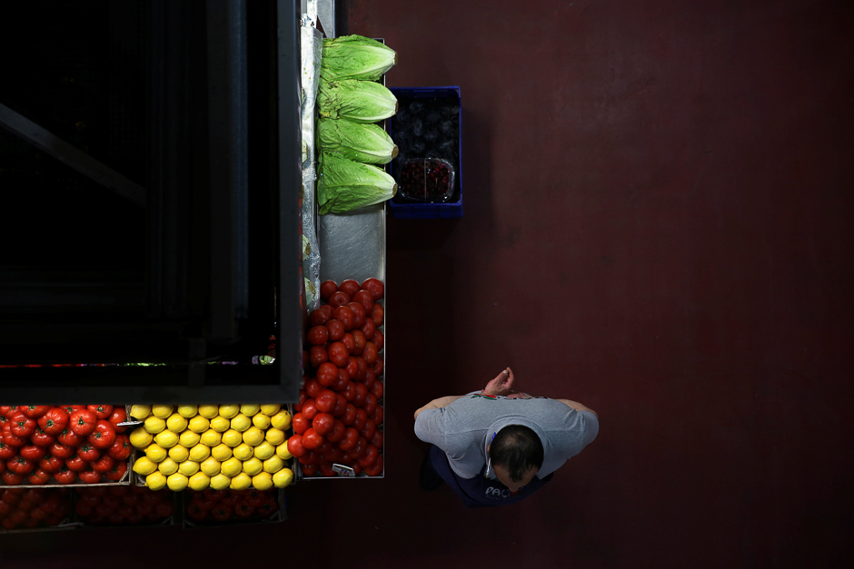 a grocer waits for customers next to his stand at a food market in madrid spain photo reuters