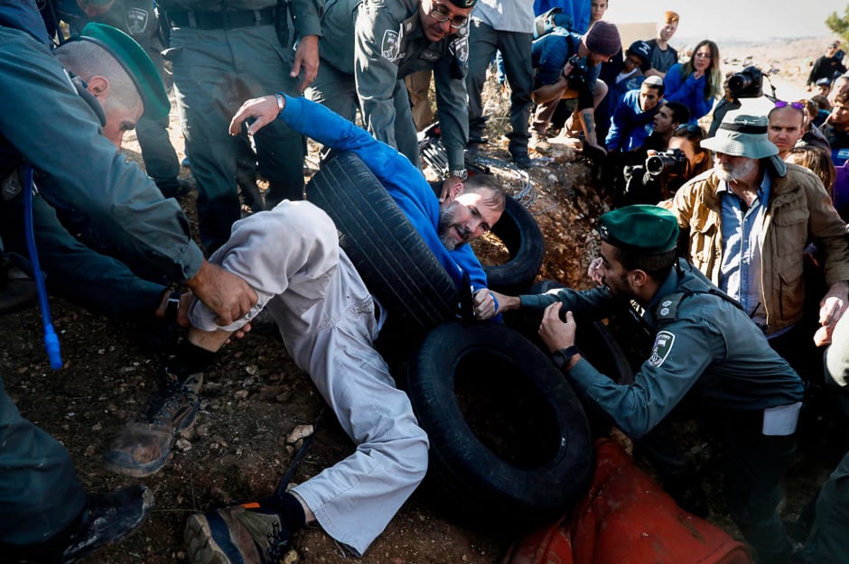 Israeli policemen retrieve Jewish settlers who barricaded themselves inside a structure built illegally on private Palestinian land, Elazar, West Bank. PHOTO: AFP