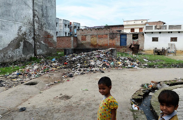 Indian children stand near a road section used as a dumpsite in Gonda district, in the Indian state of Uttar Pradesh. PHOTO: AFP