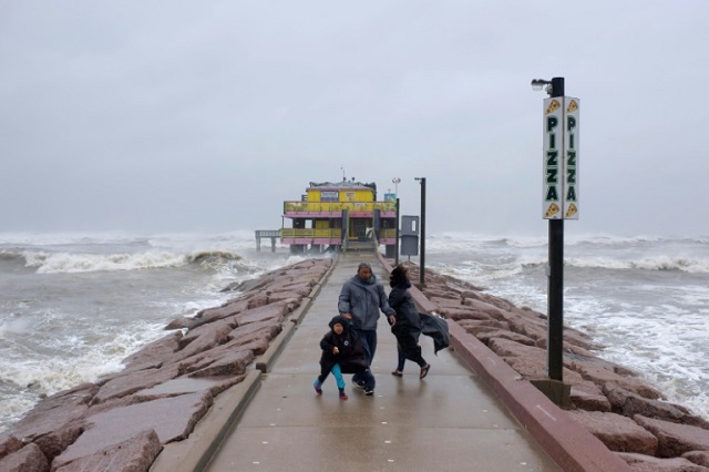 Spectators look out towards the Gulf of Mexico as the outer bands of Hurricane Delta reach Galveston, Texas on October 9, 2020. PHOTO: AFP