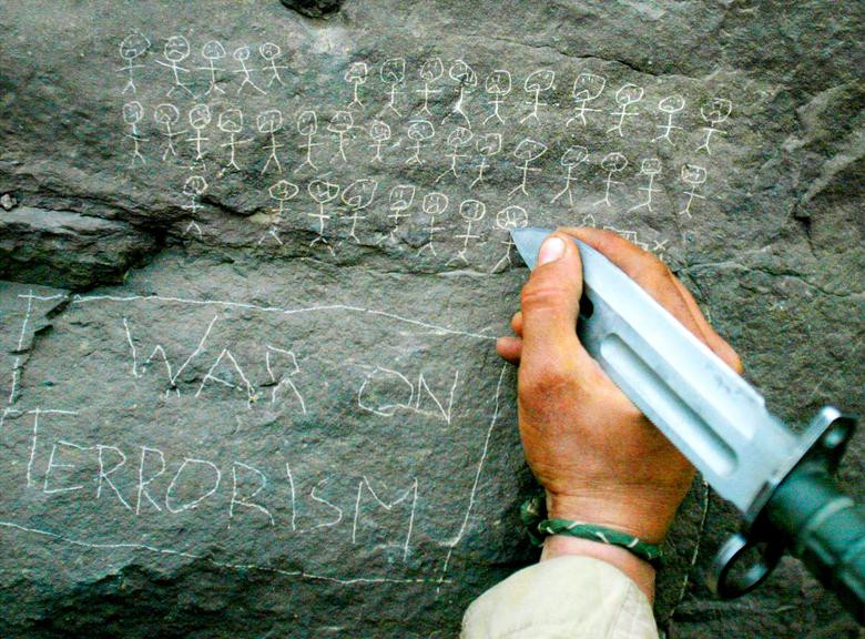 US Army 10th Mountain Division soldier Jorge Avino from Miami, Florida carves the body count that their mortar team has chalked up on a rock, near the villages of Sherkhankheyl, Marzak and Bobelkiel, in Afghanistan, March 9, 2002. [Photo: Reuters]