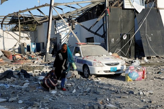 a migrant picks up her belongings from among rubble at a detention centre for mainly african migrants that was hit by an airstrike in the tajoura suburb of the libyan capital of tripoli photo reuters a migrant picks up her belongings from among rubble at a detention centre for mainly african migrants that was hit by an airstrike in the tajoura suburb of the libyan capital of tripoli photo reuters
