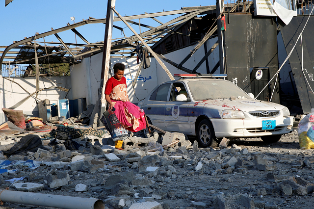 a migrant picks up clothes from among rubble of a detention centre for mainly african migrants hit by an air strike in the tajoura suburb of tripoli libya july 3 2019 photo reuters a migrant picks up clothes from among rubble of a detention centre for mainly african migrants hit by an air strike in the tajoura suburb of tripoli libya july 3 2019 photo reuters