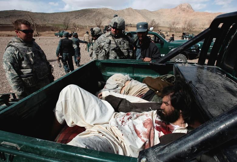 US Army soldiers and an Afghan policeman look at the bodies of Taliban fighters after a 40-minute gun battle near the village of Shajoy in Zabol province March 22, 2008. [Photo: Reuters]
