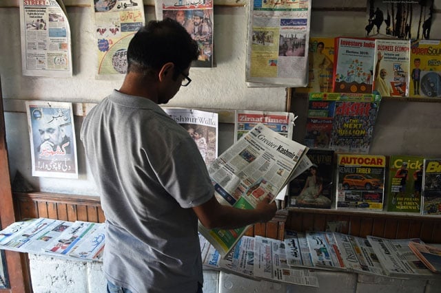 in this photo taken on july 3 2019 a man reads a newspaper at a stall in srinagar photo afp