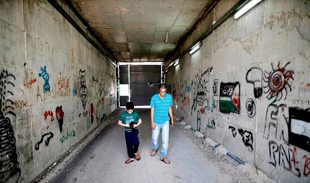 palestinian omar hajajla walks with his son through the tunnel connecting their home in jerusalem to al walajah their village in the occupied west bank on may 30 2019 photo afp palestinian omar hajajla walks with his son through the tunnel connecting their home in jerusalem to al walajah their village in the occupied west bank on may 30 2019 photo afp