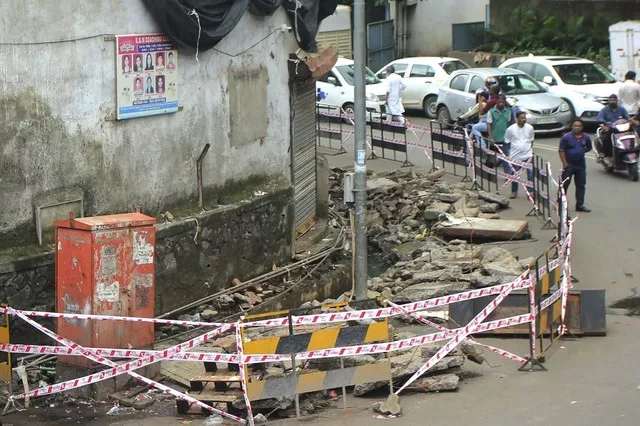 indian commuters walk past the spot where a toddler fell inside a sewage drain in mumbai photo afp indian commuters walk past the spot where a toddler fell inside a sewage drain in mumbai photo afp