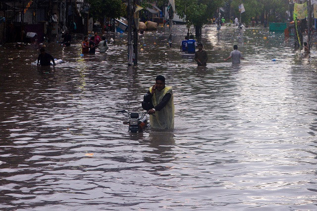 a pakistani man speaks on his phone while pushing his bike along a flooded street after heavy monsoon rains in lahore photo afp a pakistani man speaks on his phone while pushing his bike along a flooded street after heavy monsoon rains in lahore photo afp