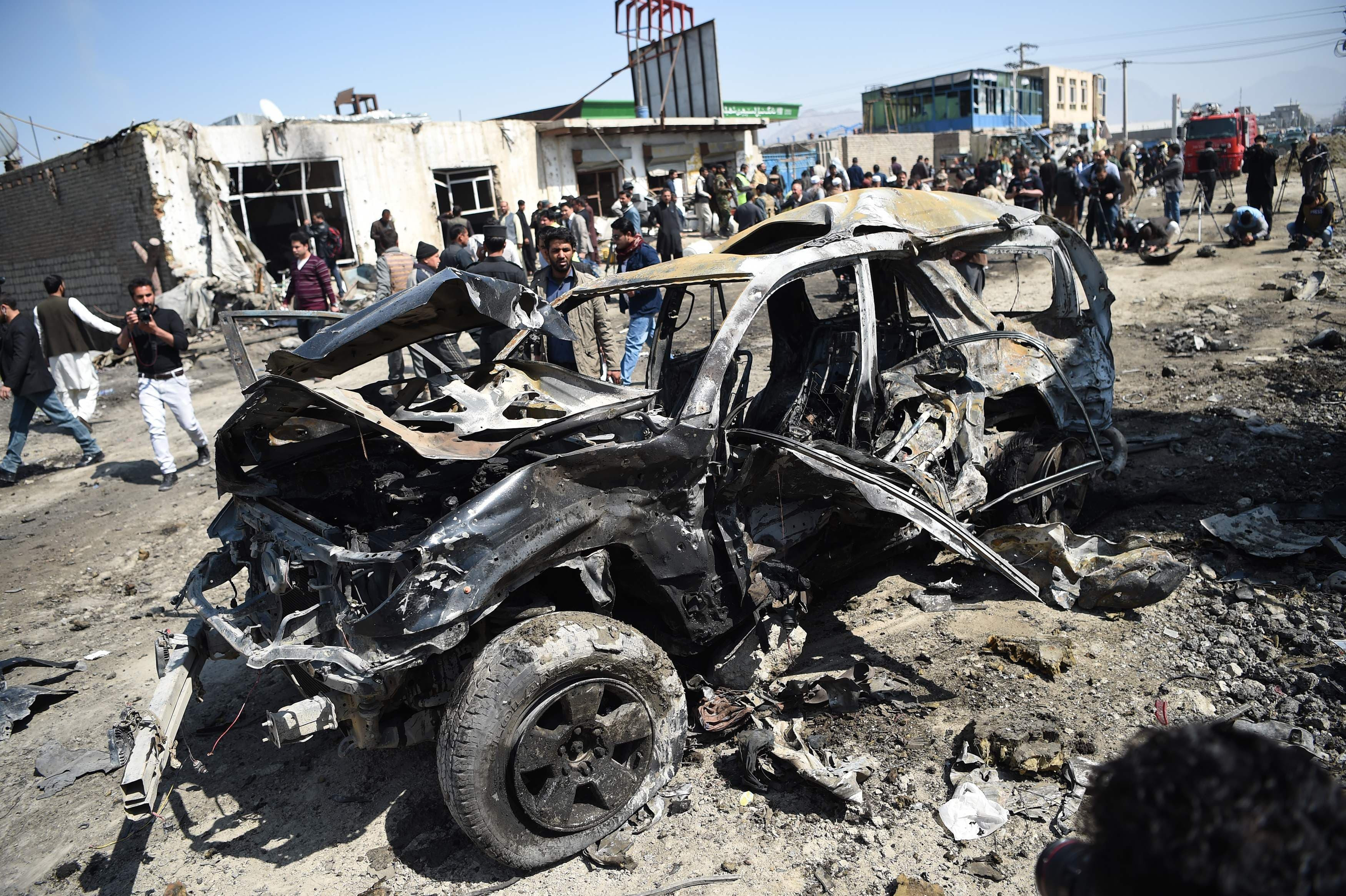 Afghan security personnel and civilians gather next to a damaged car at the site of a car bomb attack in Kabul on March 17, 2018. [Photo: AFP]