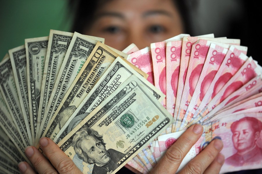 file photo shows a resident holding china s rmb and us dollar banknotes on hands in qionghai south china s hainan province photo xinhua