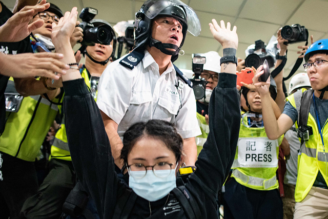 a protester gestures as a policeman looks on inside a shopping arcade in sha tin of hong kong after a rally against a controversial extradition law proposal in sha tin district of hong kong on july 14 2019 photo afp a protester gestures as a policeman looks on inside a shopping arcade in sha tin of hong kong after a rally against a controversial extradition law proposal in sha tin district of hong kong on july 14 2019 photo afp