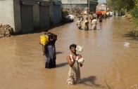 a resident catches food handouts as he along with others stands in a flooded street following monsoon rains and rising water levels of the chenab river in seetpur punjab photo reuters