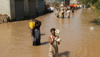 a resident catches food handouts as he along with others stands in a flooded street following monsoon rains and rising water levels of the chenab river in seetpur punjab photo reuters