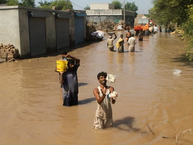 a resident catches food handouts as he along with others stands in a flooded street following monsoon rains and rising water levels of the chenab river in seetpur punjab photo reuters