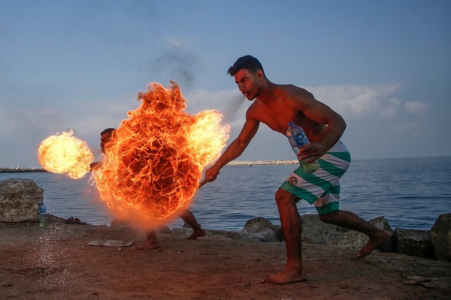 palestinian men perform fire breathing on the beach as an entertainment for children during the summer vacation in gaza city photo reuters