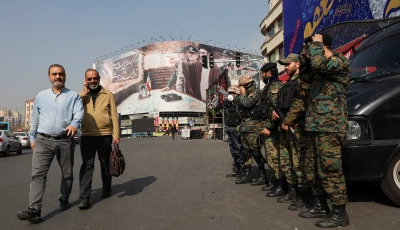 people walk past police personnel on guard near a banner featuring iran s new supreme leader mojtaba khamenei amid the u s  israeli conflict with iran in tehran iran march 14 2026 photo reuters