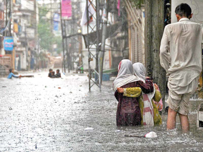 people trudge through floodwater in arampura locality of rawalpindi while an old building on jamia masjid road poses risk of crumbling down on people photos agencies