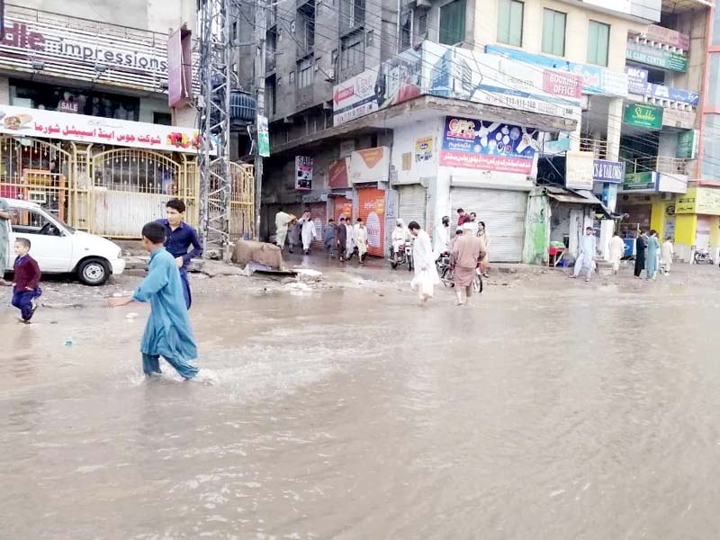 people wade through a flooded street in peshawar photo express