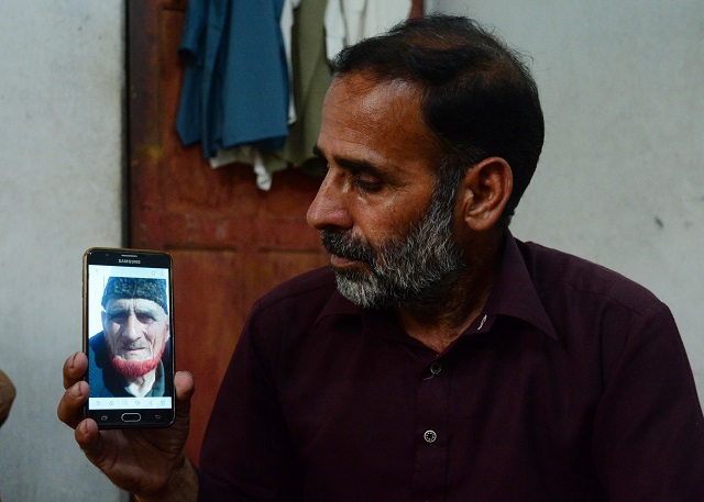 an indian kashmiri refugee mohammad yaseen rana shows a picture of his late father on his mobile phone in the manak paiyan refugee camp near muzaffarabad photo afp
