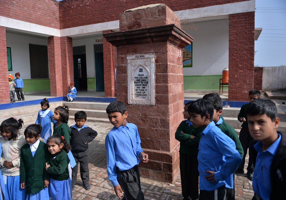 this photograph taken on october 29 2014 shows schoolchilldren stand beside a monument of the veterans of wwi at a school in village dulmial in chakwal district in punjab province around 150 kilometres south of islamabad