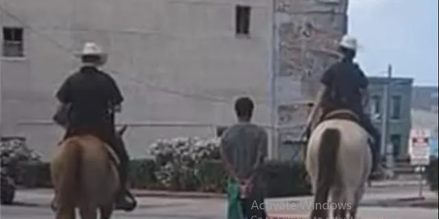 this picture shows the man in handcuffs walking with the policemen on horses photo screengrab from a video this picture shows the man in handcuffs walking with the policemen on horses photo screengrab from a video