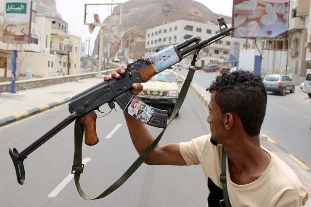 a member of yemen 039 s southern separatist holds his weapon with a picture of muneer al yafee during a funeral of brigadier general muneer al yafee and his comrades killed in a houthi missile attack in aden yemen august 7 2019 photo reuters