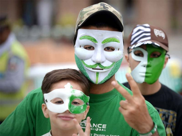 a man from the hindu community waves a national flag during a rally in peshawar left while people wear masks painted with the colours of the national flag during independence day celebrations in peshawar right photos reuters afp