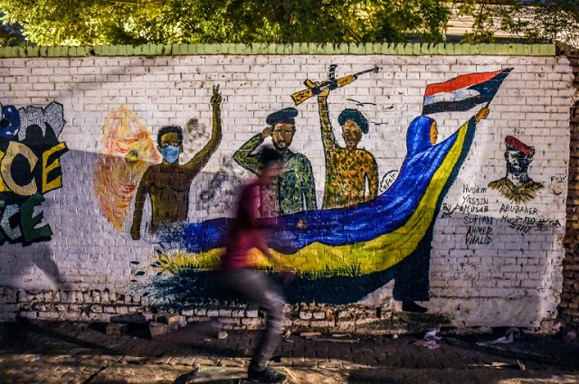 a sudanese protester runs past a mural during a demonstration near army headquarters in the capital khartoum back in april photo afp