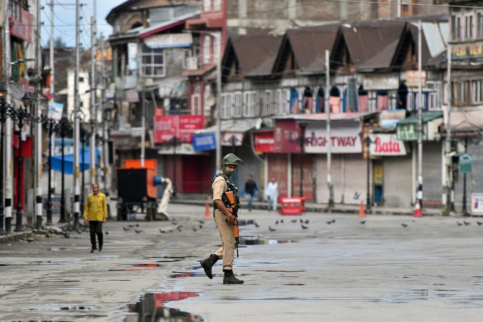 in this file photo taken on august 19 2019 an occupying force personnel patrols on a deserted road of the lal chowk area in srinagar photo afp