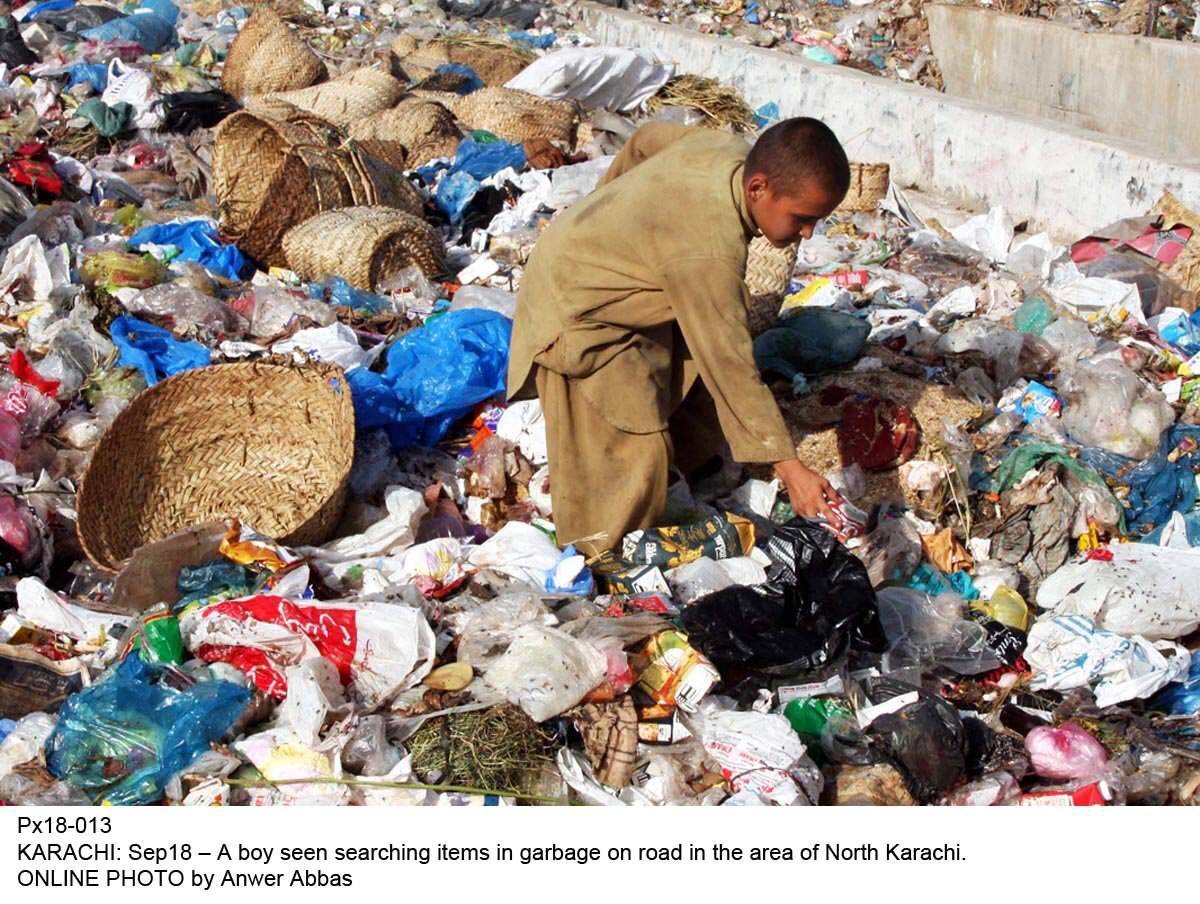 a young boy searching items in garbage on a road in karachi photo online