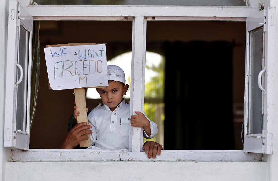 a kashmiri boy displays a placard from a window at a protest site after friday prayers during restrictions photo reuters