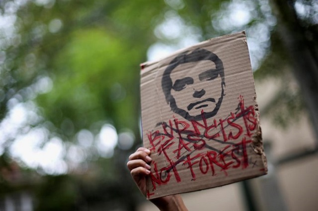 an activist holds a sign with an illustration of brazilian president jair bolsonaro as they demand more amazon rainforest protection at the embassy of brazil in mexico city mexico august 23 2019 photo reuters