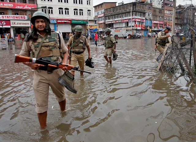 india 039 s central reserve police force crpf personnel carry their shoes as they wade through a water logged street after heavy rain in srinagar photo reuters file