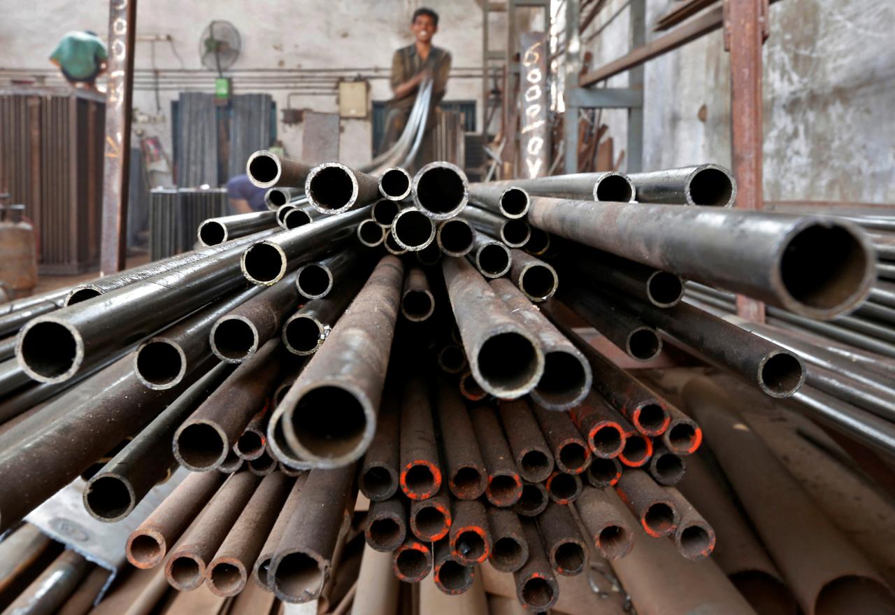 a worker stacks steel pipes in a factory photo reuters