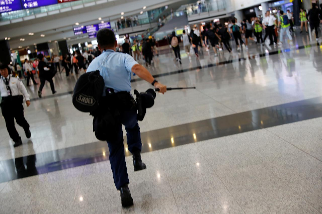 a police officer chases protesters at the airport photo reuters
