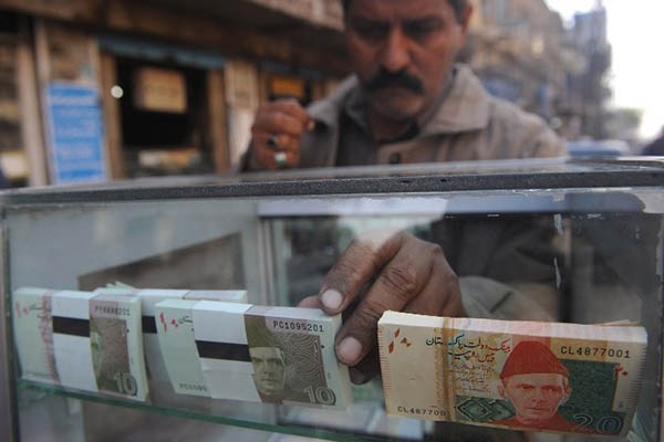 a vendor arranges 10 and 20 rupee pakistani bank notes in a display shelf at a commercial area in karachi photo afp