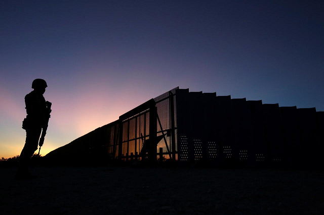 a soldier assigned to the national guard is silhouetted while keeping watch near a section of the border fence between mexico and united states photo reuters