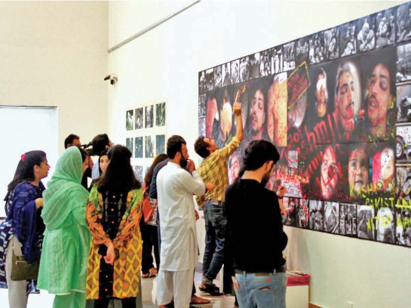 participants at the exhibition paint slogans about kashmir on photographs depicting brutalities endured by kashmiris photo express