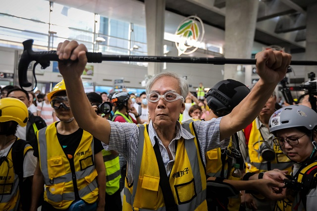 this picture taken on september 7 2019 shows quot grandpa wong quot 85 shielding protesters from the police by holding his walking stick up along with other quot silver hair quot volunteers in the tung chung district in hong kong   despite his age wong is a regular sight at hong kong 039 s street battles hobbling towards police lines placing himself in between riot officers and hardcore protesters hoping to de escalate what have now become near daily clashes photo afp