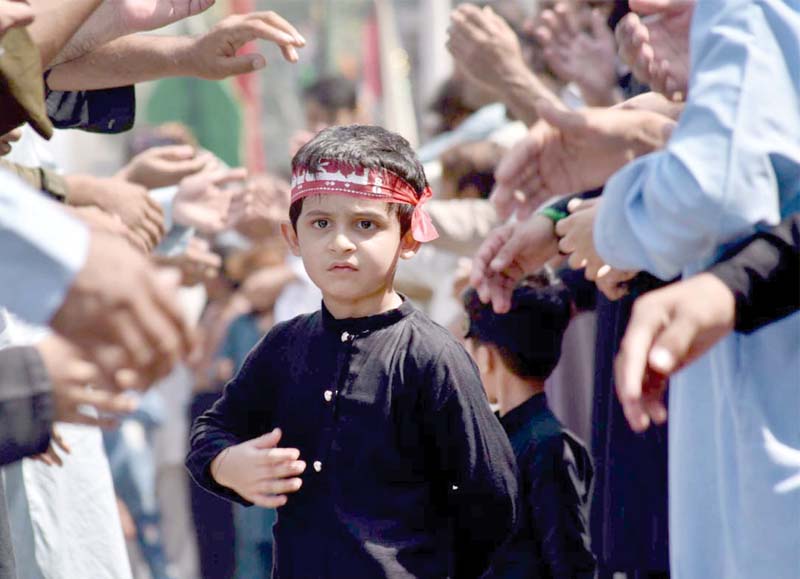 a boy stands among mourners in a muharram procession in saddar bazaar of peshawar photos app ppi