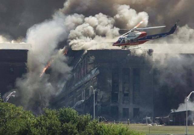 a rescue helicopter surveys damage to the pentagon as firefighters battle flames after a hijacked airplane crashed into the us military headquarters outside of washington photo reuters