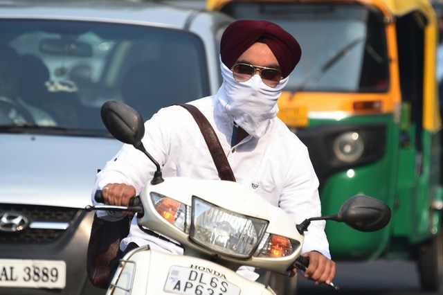 an indian biker wearing face protection against air pollution rides on the road in heavy smog in new delhi photo file