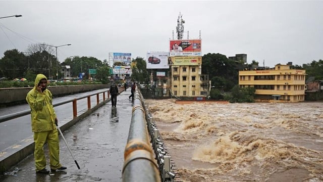 a policeman stands on a bridge as houses are submerged in the waters of the overflowing river godavari after heavy rainfall photo reuters