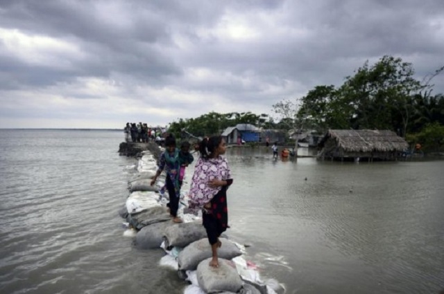 children walk over the top of a sandbag embankment that was breached by high waters in khulna after cyclone fani reached bangladesh photo afp