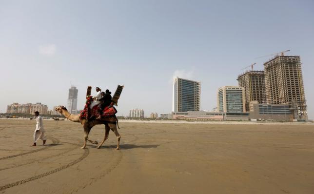 a family rides a camel past the construction of an office building and mall complex on clifton beach in karachi photo reuters