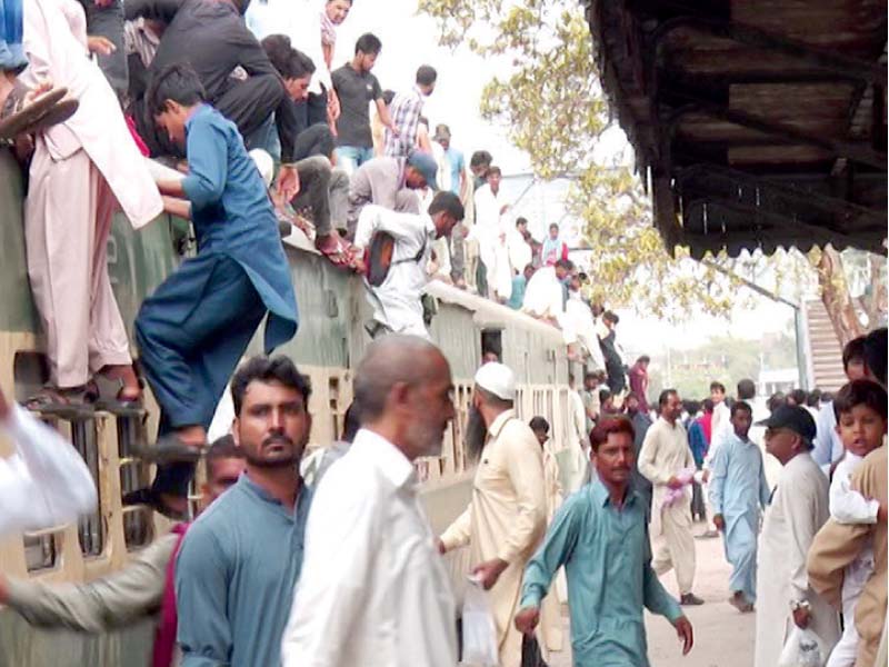 frequent travellers risk their lives by sitting on the roof of compartments due to shortage of bogies photo file